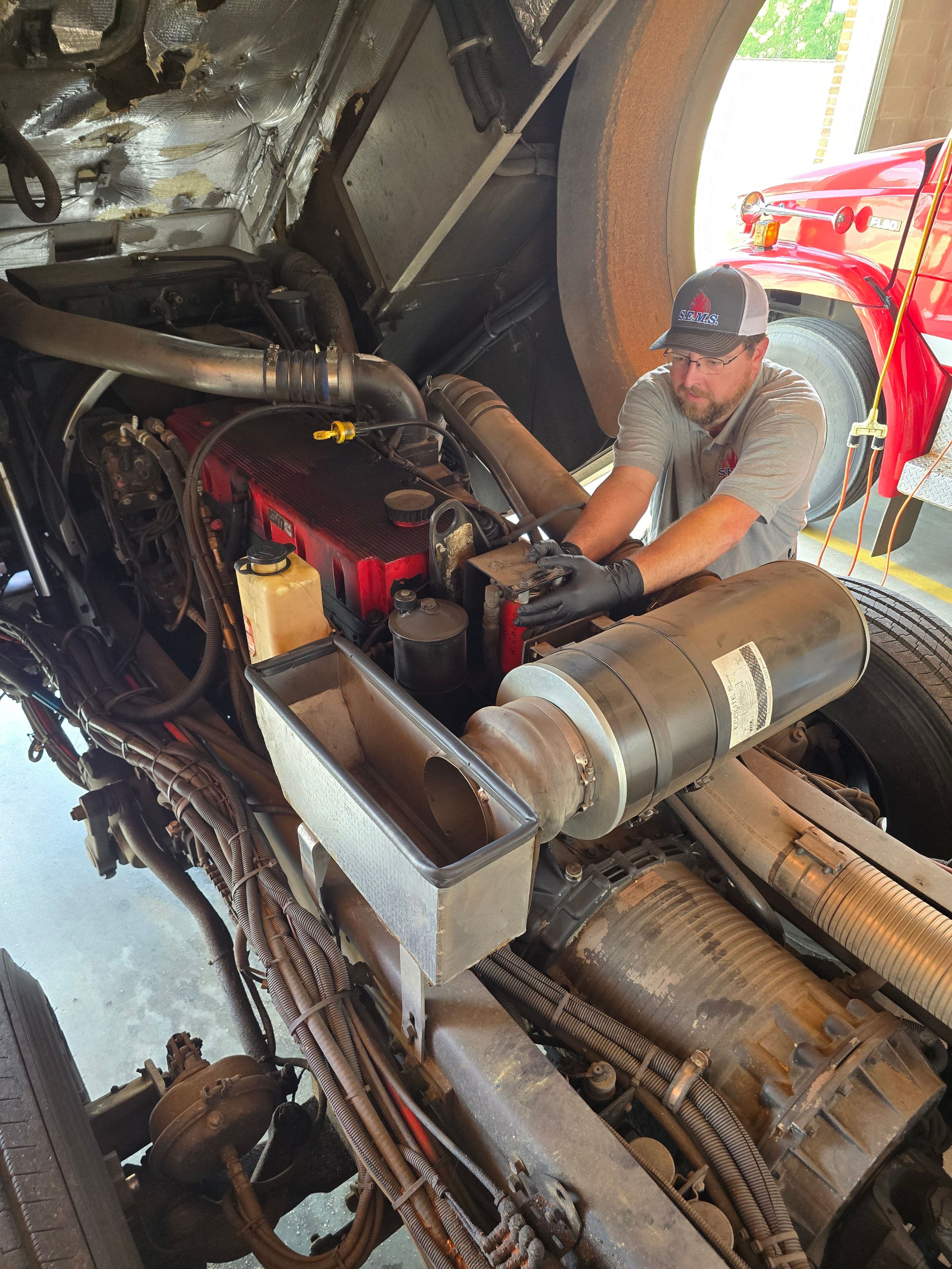 SEMS technician repairing the diesel engine of a fire truck with the cab tilted forward